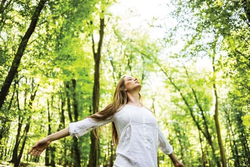 Happy woman walking in nature with natural fixes for sleep, stress, and mood.